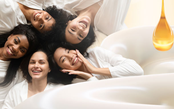 The image shows three people lying down with their heads close together, smiling and appearing happy. They are dressed in white clothing. To the right side of the image, there is a large drop of honey and a swirl of honey, suggesting a theme related to honey or sweetness. The overall atmosphere of the image is warm and joyful.