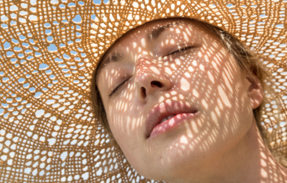 ClariantPhotoCloseup portrait of woman closed eyes wearing straw hat enjoying summer sun Pattern of