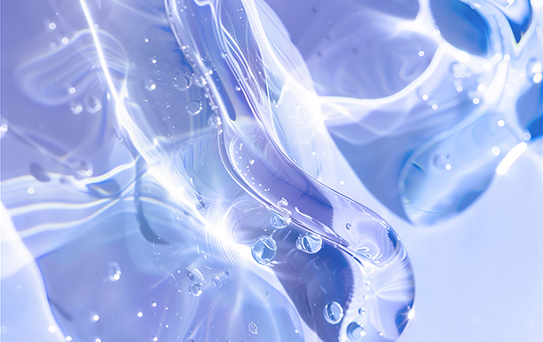 This image shows a close-up view of a translucent, blue-tinted material with smooth, flowing shapes and bubbles trapped inside. It appears to be a macro photograph of ice or a similar clear, solid substance with light reflecting and refracting through it, creating a visually interesting abstract pattern.