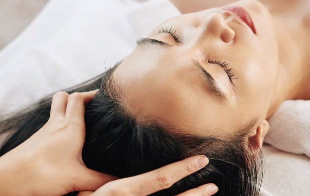 I can see a close-up of someone lying down while another person is touching or massaging their head/scalp. The central area of the image is obscured, so I can’t identify the person’s face or any details there.

If you want, I can also help describe the visible parts in more detail or infer the likely context of the scene.