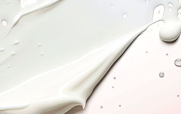 The image appears to show a close-up of a white creamy liquid or paint-like substance spreading across a light surface, with a few droplets scattered around.